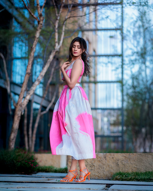 Blush pink and ivory printed raw silk skirt with crop top, model standing in a garden walkway in soft side profile