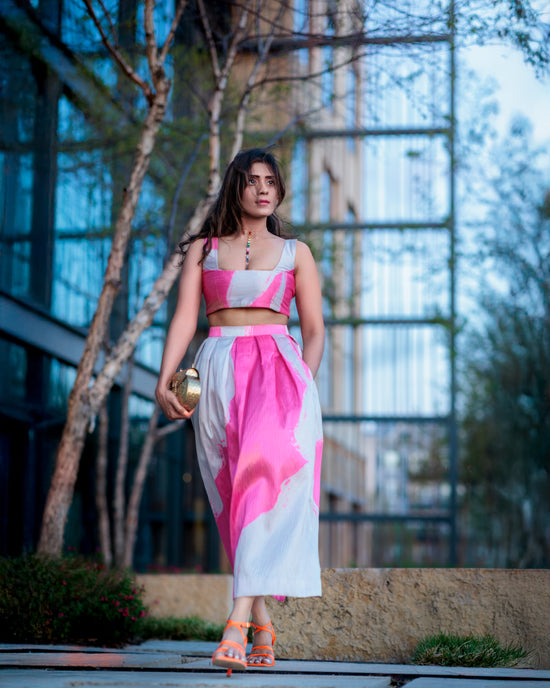 Model walking in a pink and ivory silk skirt, styled with heels in an outdoor urban setting
