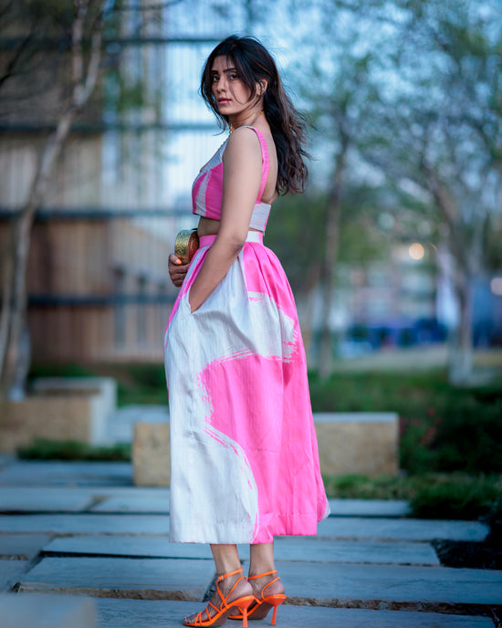 Woman in a pink and white dress standing outdoors with blurred background