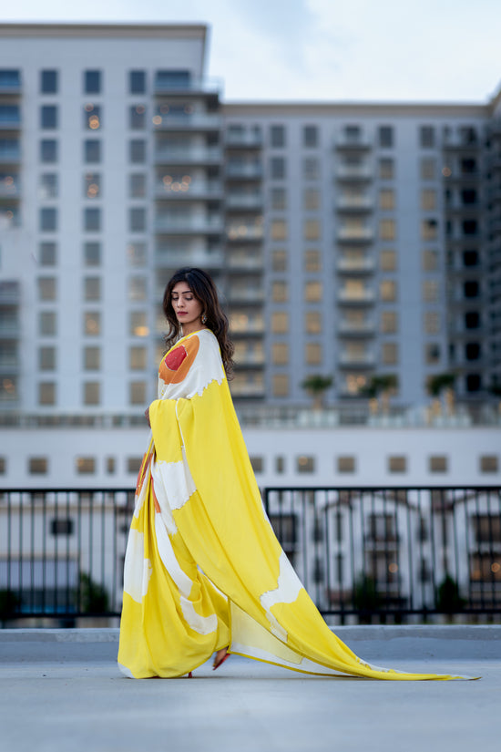 Woman in a yellow and white dress standing on a rooftop with city buildings in the background