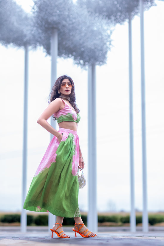 Model in pink and green abstract print raw silk midi skirt with A-line silhouette, styled for modern statement dressing