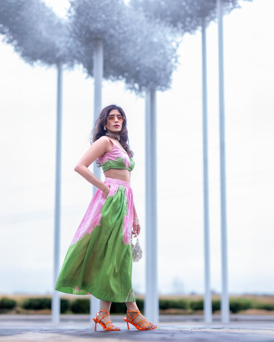Model in pink and green abstract print raw silk midi skirt with A-line silhouette, styled for modern statement dressing